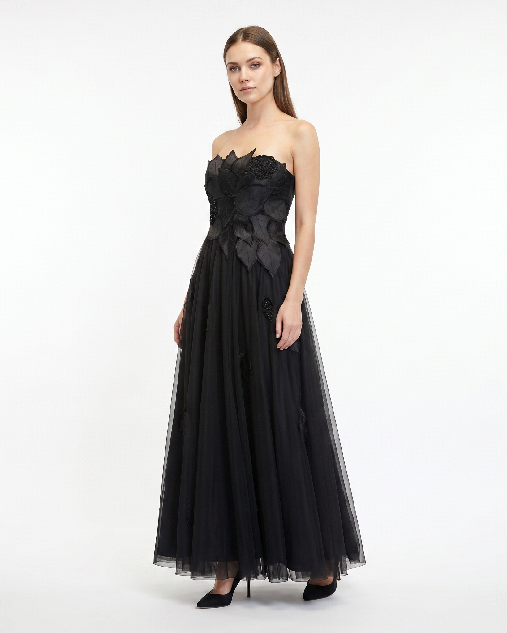 Woman wearing a black strapless gown with floral details on a white background