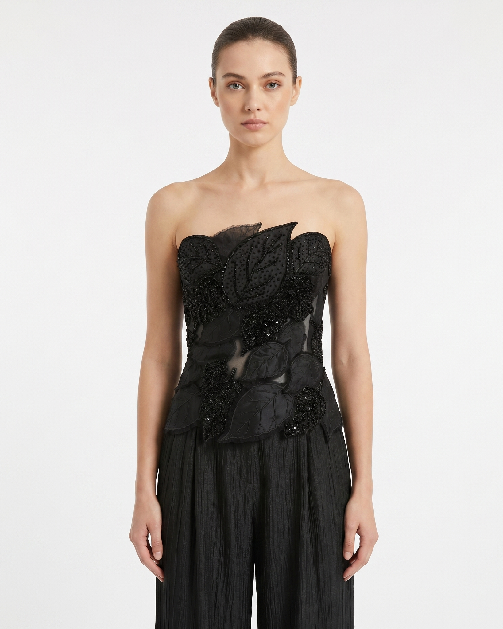 Woman wearing a black strapless top with floral details on a white background